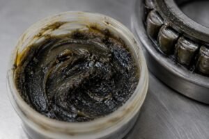Contaminated bearing grease sample showing dark discoloration and embedded particles